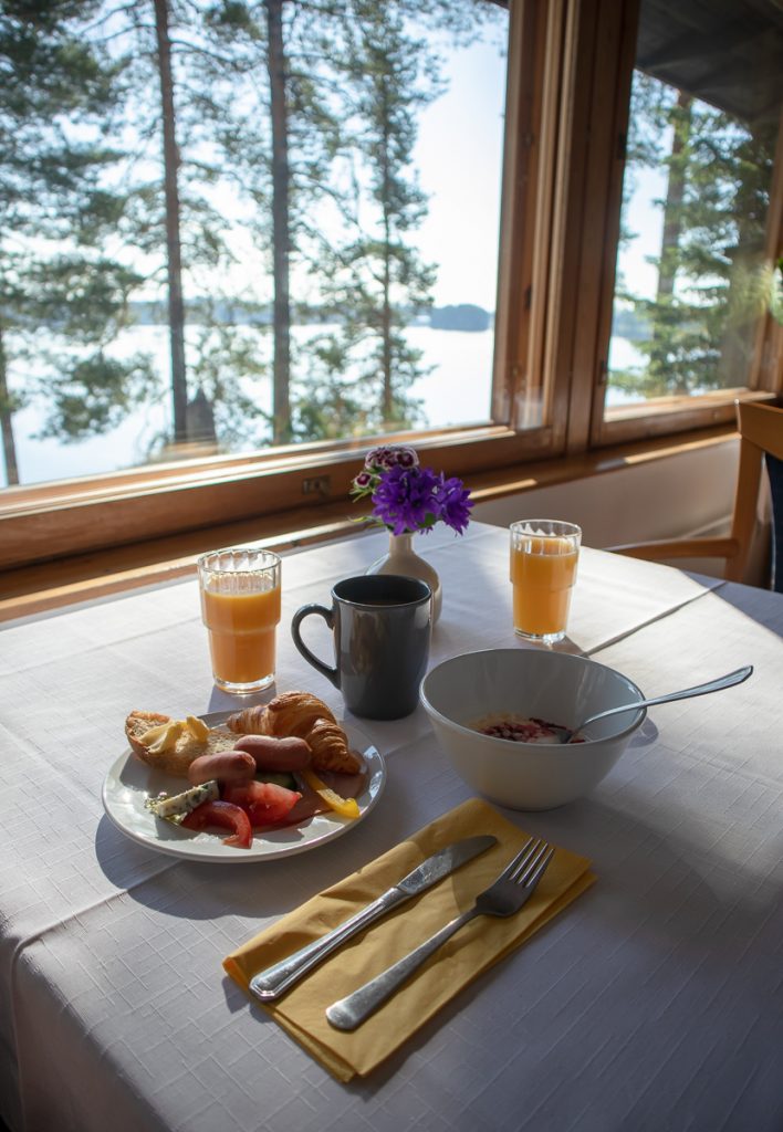 Näkymä Hotelli Kalevalan ravintolasta järvelle, sekä aamiaistarpeita pöydällä.